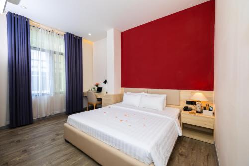 una camera con un grande letto con una parete rossa di Khách sạn Phước Lộc Thọ 2 - 福禄寿 ad Ho Chi Minh