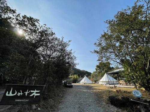 a gravel road with two white tents and a sign at Yamamizuki in Shimanto