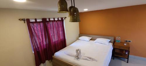 a bedroom with a bed with white sheets and red curtains at Gitanjali Forest Retreat in Bāghmundi