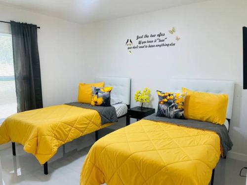 a bedroom with two beds with yellow sheets at White house 1 in Lehigh Acres