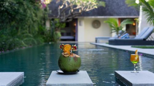 a vase sitting on a table in the water with a drink at Casa Mateo Villa in Seminyak