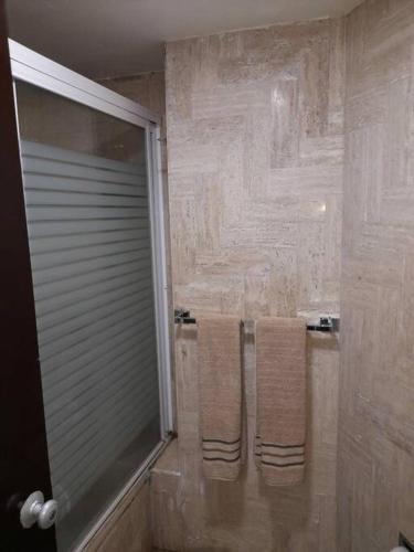 a bathroom with three towels hanging on a shower at Departamento con hermosa vista al mar y acceso a playa, 2 albercas in Acapulco