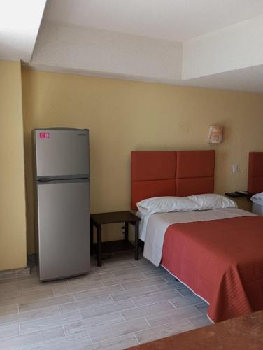 a room with a refrigerator and a bed and a table at Departamento con hermosa vista al mar y acceso a playa, 2 albercas in Acapulco