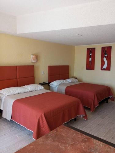 a hotel room with two beds with red covers at Departamento con hermosa vista al mar y acceso a playa, 2 albercas in Acapulco