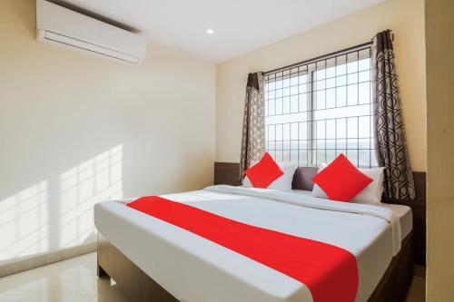 a bedroom with a bed with red pillows and a window at OYO Anu Grand in Visakhapatnam