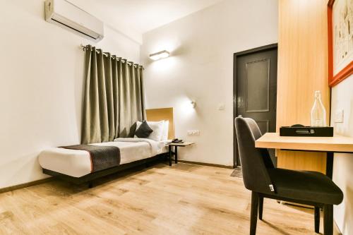 a bedroom with a bed and a desk with a chair at Super Townhouse 182 Menka in Patna