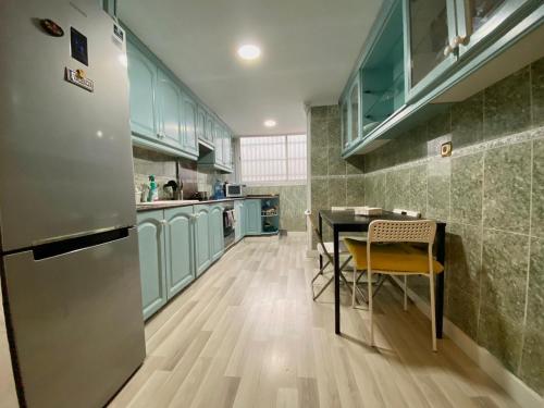 a kitchen with green cabinets and a table and a refrigerator at Alojamiento cerca de la Playa in Valencia