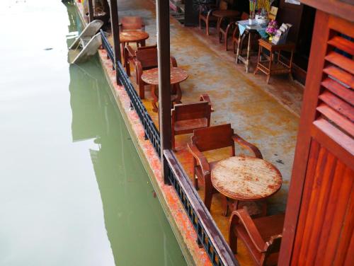a row of wooden tables and chairs in a restaurant at Thanicha Resort Amphawa in Amphawa