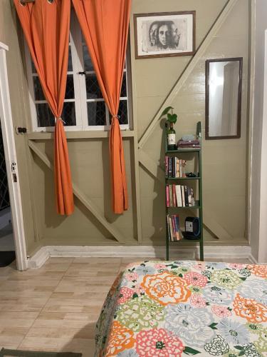 a bedroom with a bed with an orange curtain at Adella's Blue Mountain Coffee Farmstay in Kingston