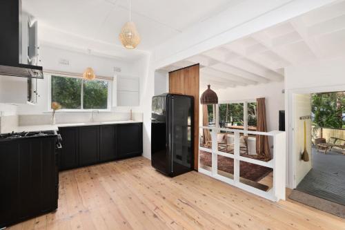 a kitchen with a black refrigerator in a room at Bungalow 127 at Avalon pde, 800m walk to beach in Avalon