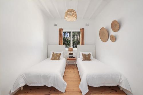 two beds in a room with white walls at Bungalow 127 at Avalon pde, 800m walk to beach in Avalon