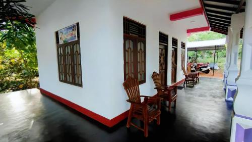 Cette chambre est dotée de chaises et d'un mur blanc. dans l'établissement New Dinu Holiday Inn, à Kataragama