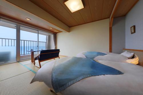 two beds in a room with a large window at Ako Onsen Shokichi in Ako