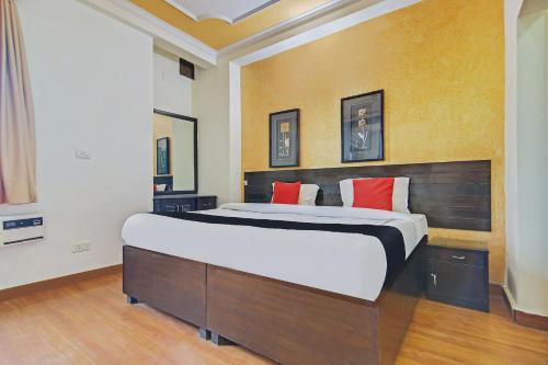 een slaapkamer met een groot bed met rode kussens bij Super Capital O Tipsyy 006 Near Aravali Biodiversity Park in Gurgaon