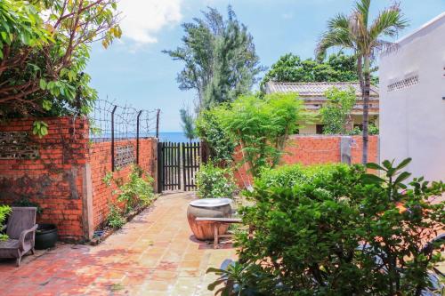 a garden with a bench and a brick fence at Biệt thự Tứ Quý Phan Thiết in Tiến Thành