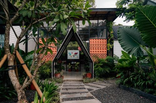 a house with a door in the middle of a garden at The Jungle Hostel Canggu in Canggu