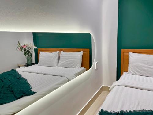 two beds in a room with green and white at Joi Hospitality - Anthony in Vung Tau