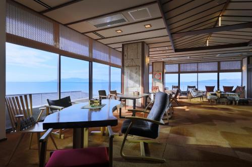 a restaurant with tables and chairs and a view of the ocean at Ako Onsen Shokichi in Ako