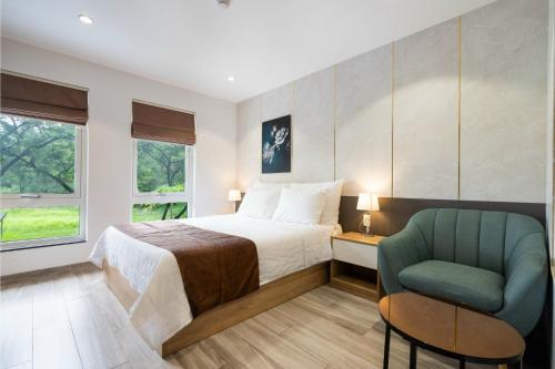 a bedroom with a bed and a green chair at NiNa APARTHOTEL in Ho Chi Minh City