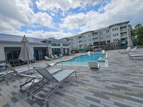 a swimming pool with lounge chairs and an umbrella at BeautifulApartmentNeartheAirport&RiverCity in Jacksonville