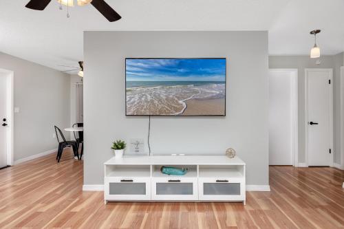 a living room with a tv on a white wall at Sunny Escape: Vibrant Pool Home in Port Richey