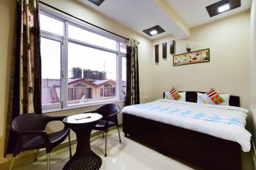 a bedroom with a bed and a window and a table and chairs at OYO Home Sam Villa Studio in Shimla