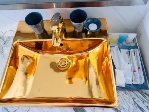 un lavabo de oro en un baño con tazas en una encimera en Ks View Biển Bể Bơi Dát Vàng GOLDENBAY ĐÀ NẴNG, en Da Nang
