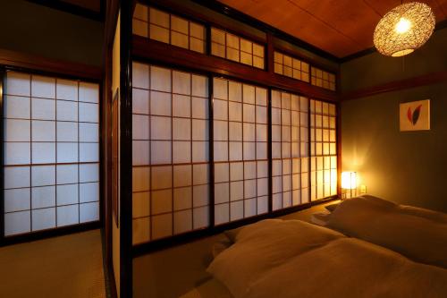 a bed in a room with windows and a lamp at 貸切民泊宿 だんねだんね Private guest house Danne-Danne in Ōno