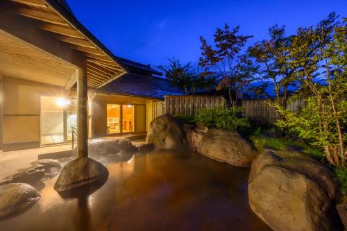 a house with a pond in the yard at night at Hotel Symphony Annex Sagae Onsen in Sagae