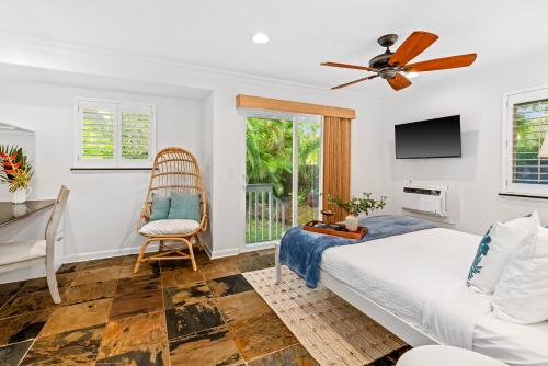 a bedroom with a bed and a fan and a chair at Cute 2BR Cottage w AC close to beaches in Koloa