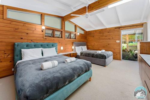 Aircabin - KANGY ANGY - Rural Retreat - 8 Beds House في Tuggerah: غرفة نوم بسريرين في غرفة بجدران خشبية