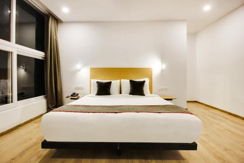 a bedroom with a large white bed with black pillows at Super townhouse moosapet Rcc Prime in Hyderabad