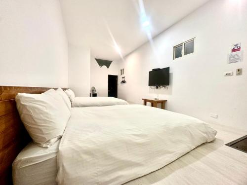 a bedroom with two white beds and a tv at Nanwan254 Homestay in Nanwan