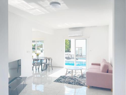 un soggiorno con divano rosa e tavolo di White Mountain Pool Villas a Paphos