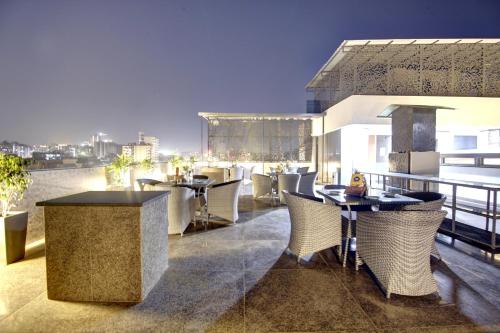 a restaurant with tables and chairs on a balcony at Saltstayz Premier - Near Golf Course Road & Sector 57 in Gurgaon