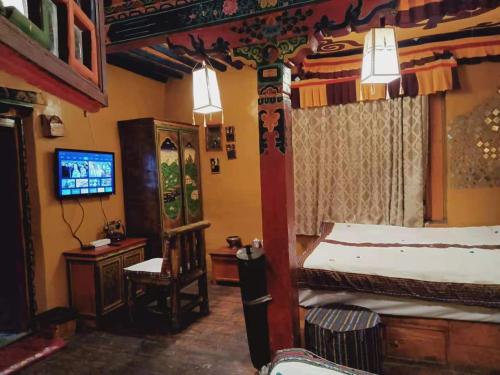 um quarto com uma cama, uma cadeira e uma televisão em Shambhala Palace Hotel em Lhasa