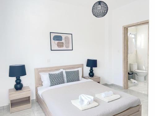 a white bedroom with a bed with two towels on it at White Mountain Pool Villas in Paphos City