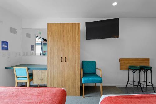 a room with a table and two chairs and a television at Bella Vista Motel & Apartments Christchurch in Christchurch