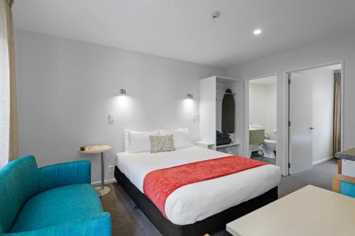 a hotel room with a bed and a blue chair at Bella Vista Motel & Apartments Christchurch in Christchurch