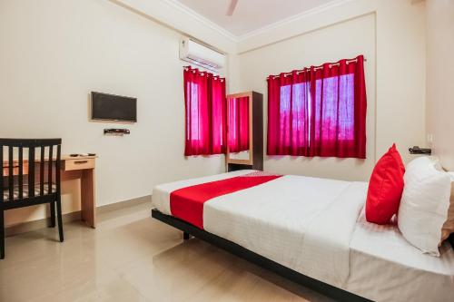 Schlafzimmer mit einem Bett mit roten Vorhängen und einem Schreibtisch in der Unterkunft Flagship Neknampur Near Golconda Fort in Haidar Sāhibgūda