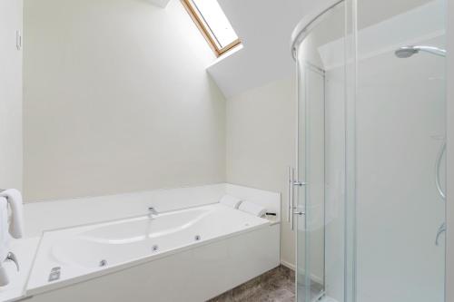 a white bathroom with a tub and a shower at Bella Vista Motel & Apartments Christchurch in Christchurch