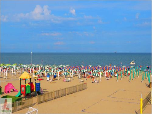 a beach with a large group of people and the ocean at Spacious apartment close to the beach - Beahost in Rosolina Mare