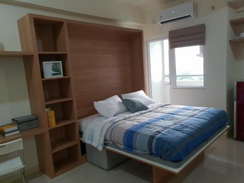 ein Schlafzimmer mit einem Bett und einem Bücherregal in der Unterkunft Apartemen Green Pramuka City Tipe Studio (1 BR) in Jakarta