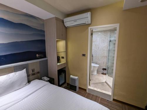 ein Schlafzimmer mit einem Bett und ein Badezimmer mit einer Dusche in der Unterkunft Macchi Hotel - Taipei in Taipeh