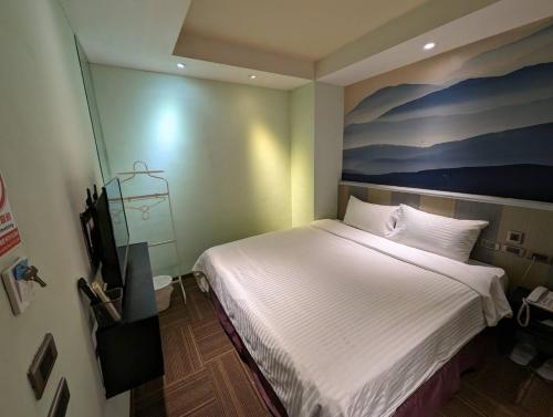 a bedroom with a bed with a painting on the wall at Macchi Hotel - Taipei in Taipei
