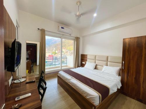 a hotel room with a bed and a large window at Hotel Manikut in Rishīkesh