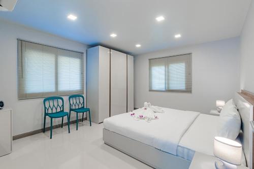 a bedroom with a white bed and two chairs at Kamala Beach Estate Resort - SHA Extra Plus in Kamala Beach