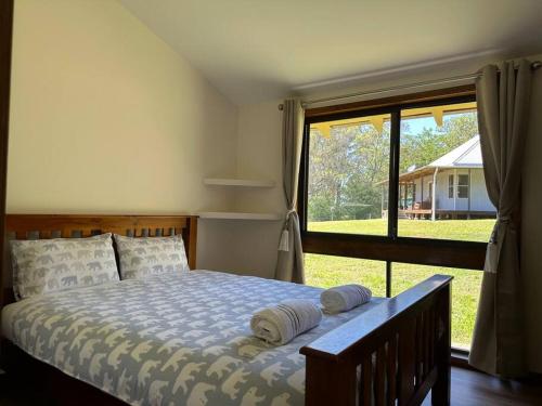 Aircabin｜KANGY ANGY｜Lovely｜4 Beds Holiday House في Tuggerah: غرفة نوم بسرير ونافذة كبيرة