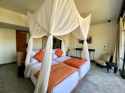a bedroom with two beds and a canopy bed at MAUA Nusa Penida Bali in Nusa Penida