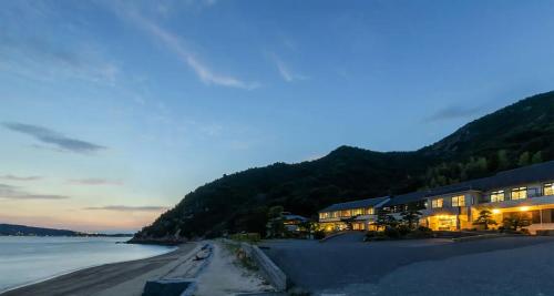 a building on the beach at night with the water at Sennenmatsu in Imabari